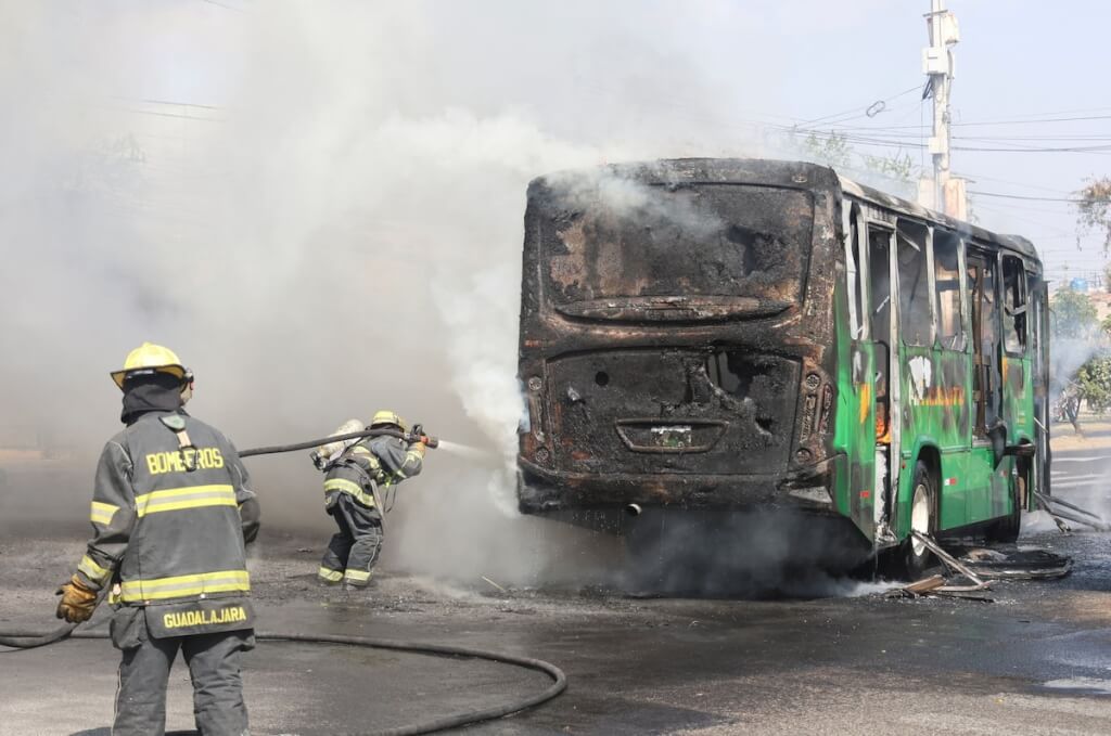墨西哥城市瓜達拉哈拉一輛被用作路障的車遭縱火，消防員趕往撲滅。（路透社） 圖：中央社提供