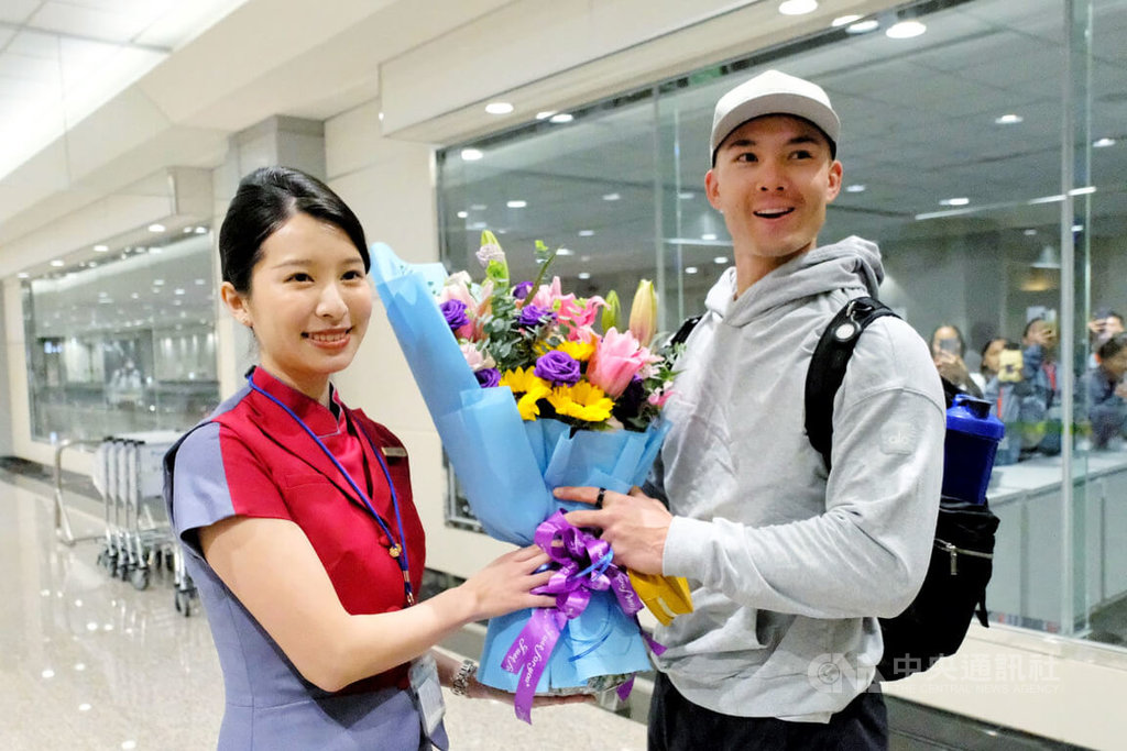 台美混血棒球好手費柴德（Stuart Fairchild）（右）26日晚間搭機順利抵達桃園國際機場，27日就會參與經典賽台灣隊練球，華航地勤人員在機場獻花表達歡迎之意。  圖/中央社