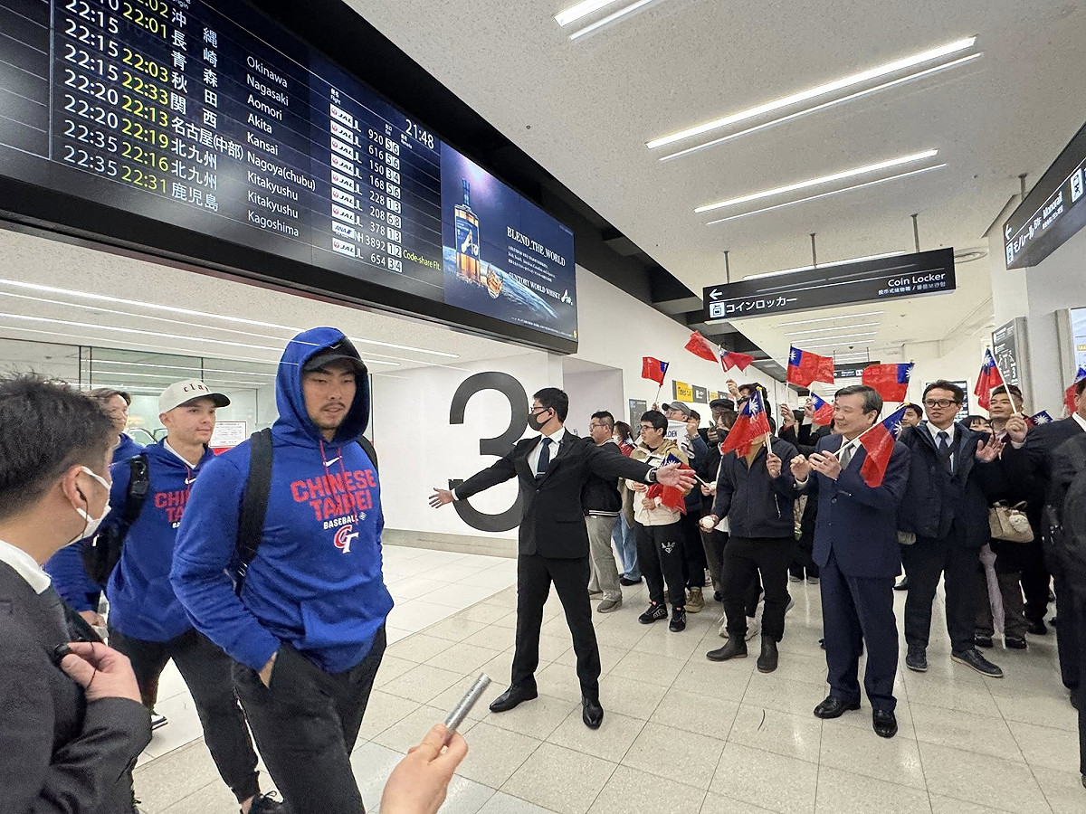 台灣隊抵達東京羽田機場後，現場駐處官員及僑胞舉布條及揮舞國旗迎接他們到來。 圖：翻攝李逸洋臉書