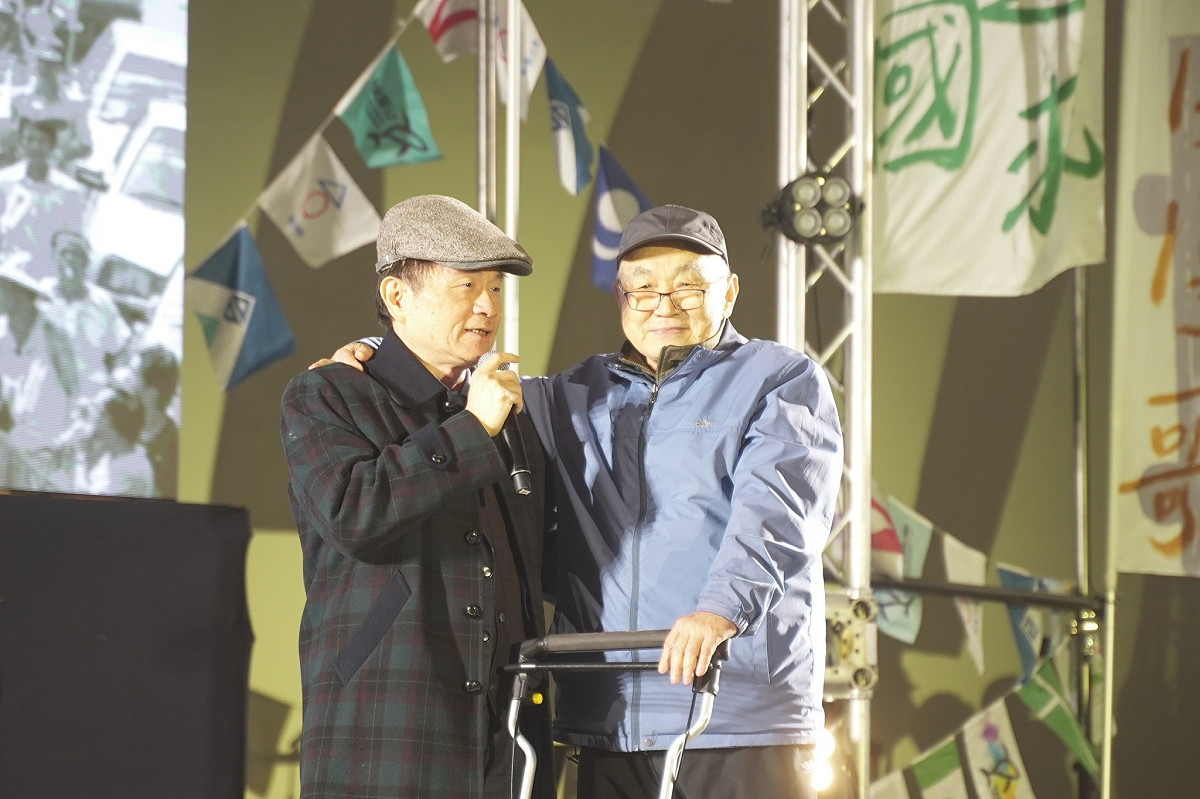 「反侵略日歌唱節」上，國史館長陳儀深（左）在大合唱環節，與最後一位「返鄉禁令」黑名單黃文雄（右）同台。 圖：台灣經濟民主連合 提供
