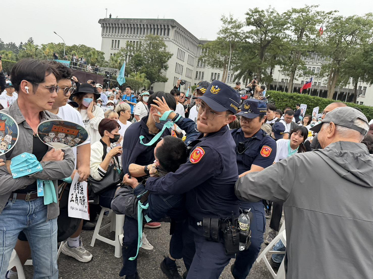 網紅「吃屎哥」游兆霖在活動場內高喊「柯文哲貪污」，瞬間遭警方壓制拖走。 圖：金大鈞/攝