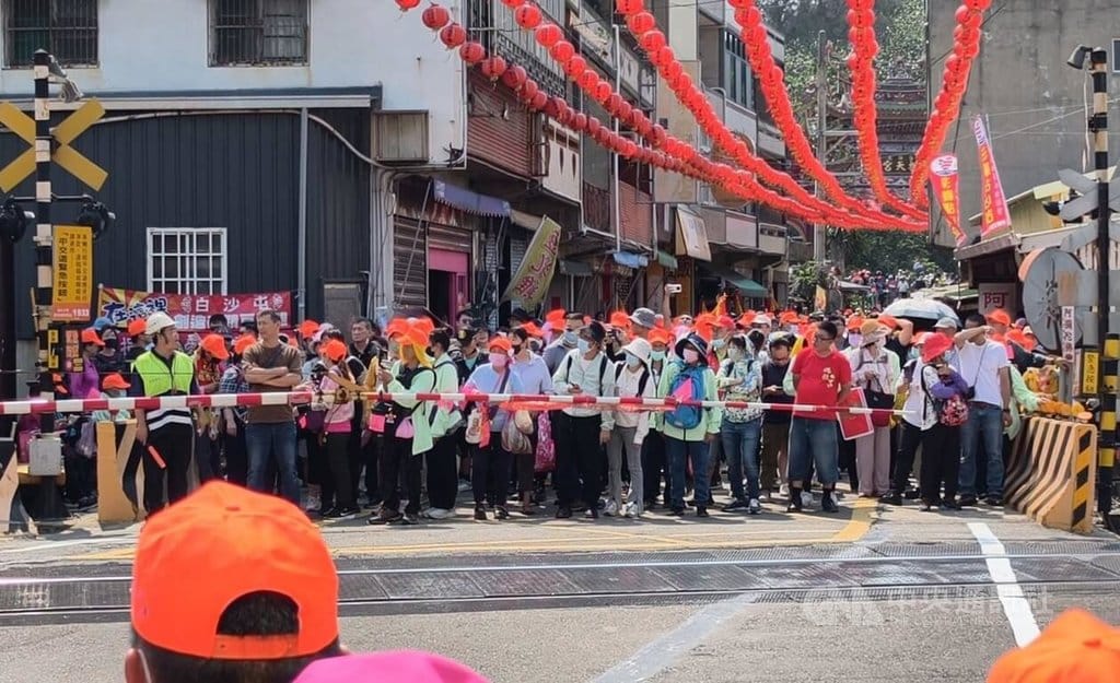 苗栗縣通霄鎮白沙屯拱天宮媽祖徒步往北港進香活動12日深夜將登轎啟程，大批香燈腳自上午陸續湧入白沙屯地區。圖為進香民眾在平交道前等待火車通過。 圖：中央社提供