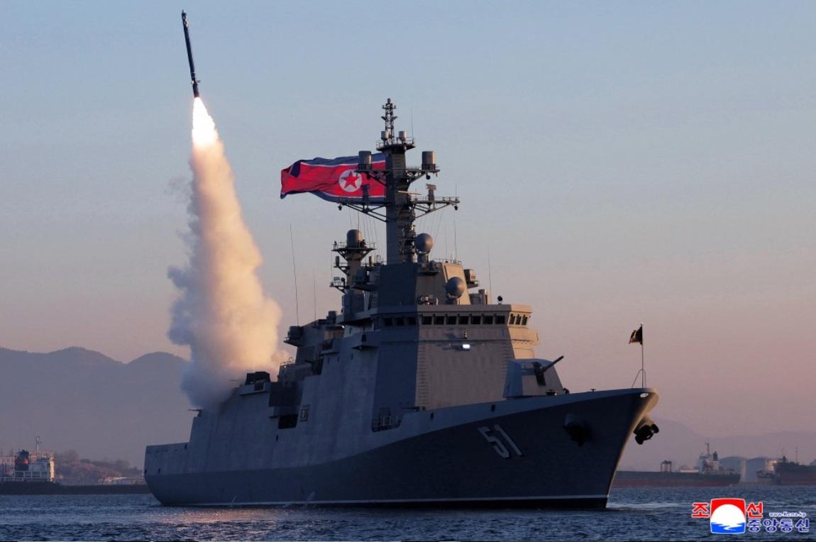 「崔賢號」驅逐艦試射2枚戰略巡航導彈與3枚反艦導彈。但背景可見岸上工業設施、山脈及港區建築，懷疑可能在港口內或近岸水域完成。 圖：翻攝朝中社