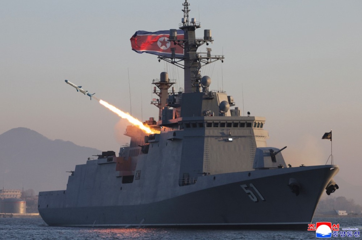 「崔賢號」驅逐艦試射2枚戰略巡航導彈與3枚反艦導彈。但背景可見岸上工業設施、山脈及港區建築，懷疑可能在港口內或近岸水域完成。 圖：翻攝朝中社
