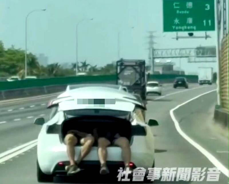白色特斯拉後車廂半開，2名男子躺在其中，畫面超危險。 圖：翻攝自《社會事新聞影音》