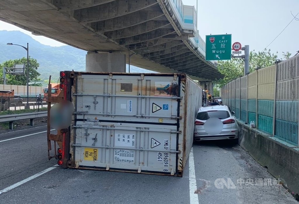 台64線新北市八里區往五股方向上匝道口附近，23日上午發生貨櫃車不明原因翻覆事故，整輛車往前衝撞到路旁停放車輛，所幸未釀人員傷亡，詳細肇事原因有待後續調查釐清。中央社記者王鴻國攝　115年4月23日