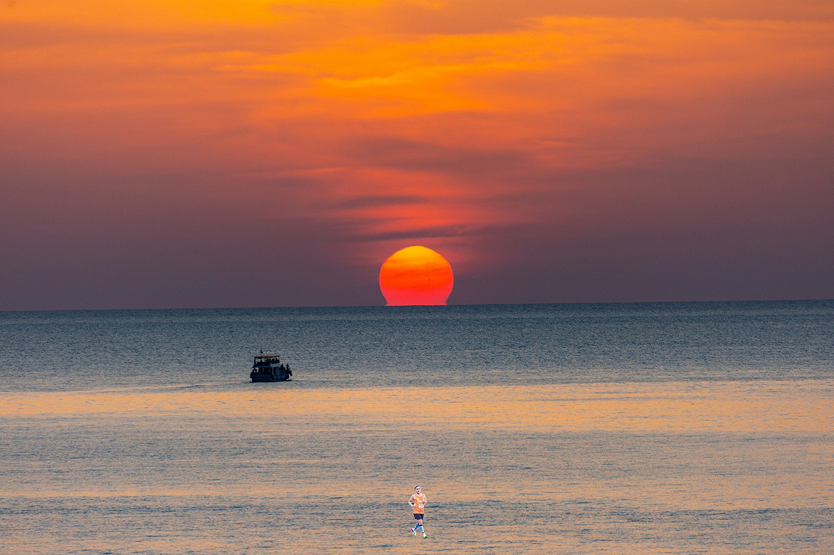 畫面中如蛋黃般的夕陽，落入被染成橘紅色的水平面時，下緣彷彿有其他太陽接住，呈現酒杯形狀。 圖：取自鄭明典臉書