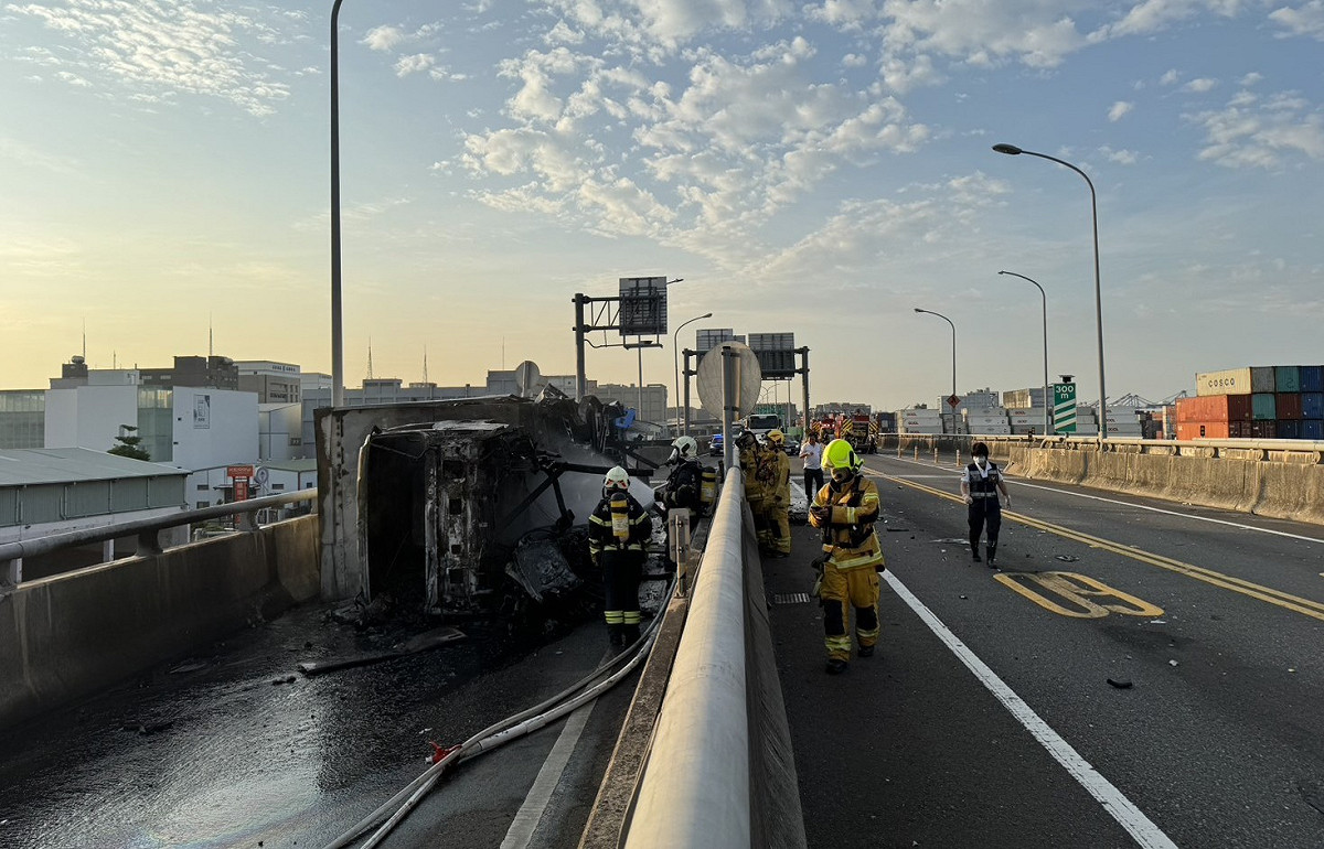 新生路高架橋北上往第二貨櫃中心匝道口，一部營業大貨車翻覆於路中並起火燃燒。 圖：高市警前鎮分局/提供