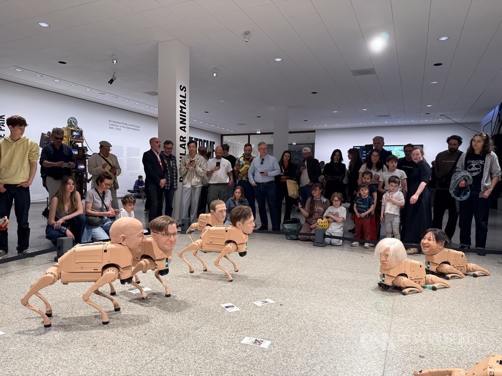 美國數位藝術家Beeple裝置作品「常規動物」於柏林新國家美術館展出，機器狗裝上獨裁者、改變世界審美的藝術家與科技巨頭臉孔，在展場中移動並透過人工智慧生成圖像，吸引觀眾圍觀。中央社記者林尚縈柏林攝　115年5月5日 圖：中央社提供