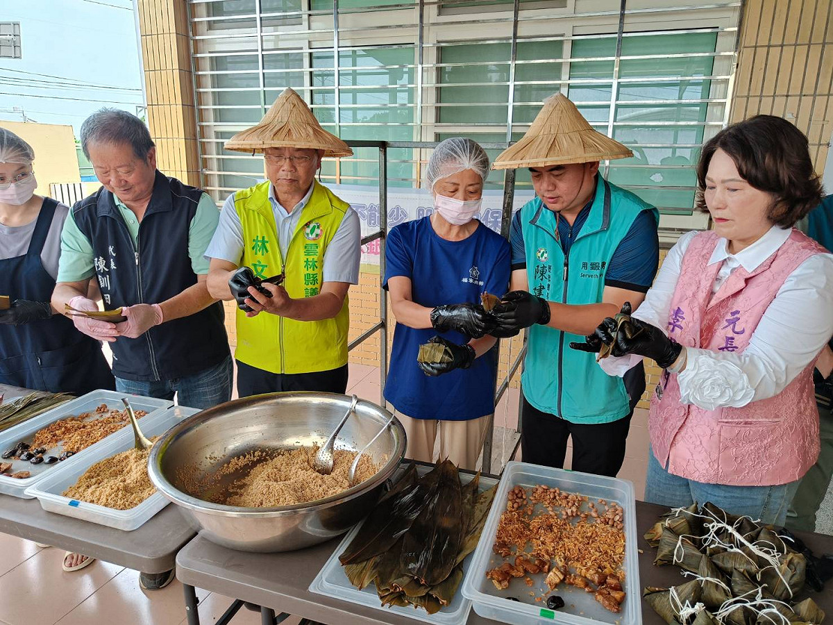 褒忠鄉長陳建名及多位與會的貴賓一同在社區媽媽的指導下，親手學包粽。 圖：唐復年/攝