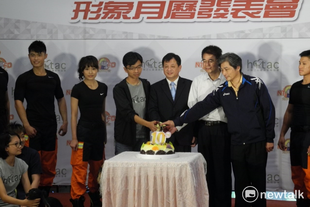 新北消防月曆邁入10週年，消防局副局長陳崇岳（中間西裝者）與來賓切蛋糕慶祝。 圖：王峻昌/攝