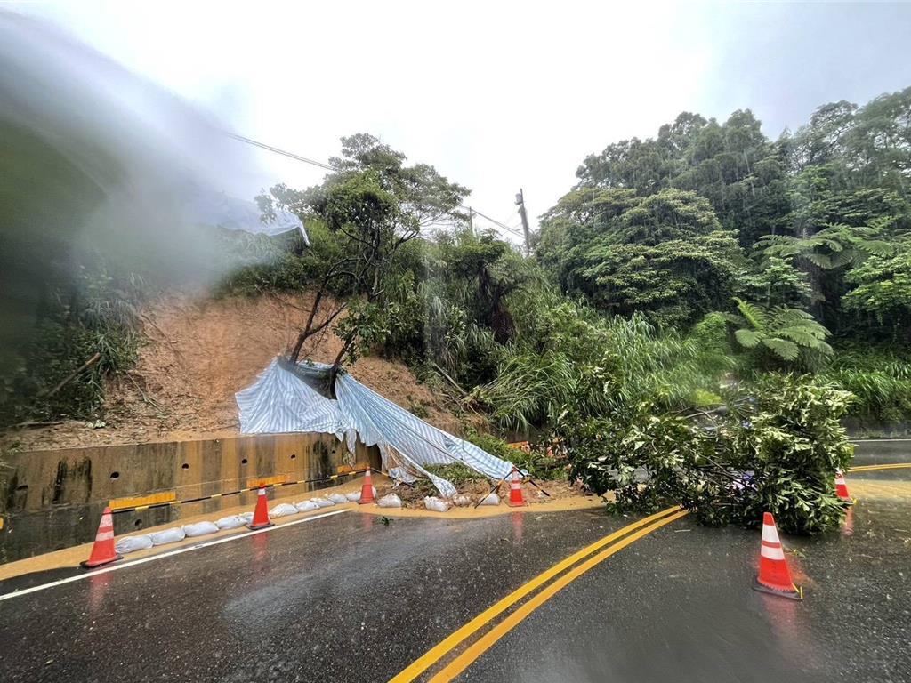蘆竹區六福一路的1處山坡的土石與樹木滑落，佔據一車道。 圖：蘆竹警分局／提供