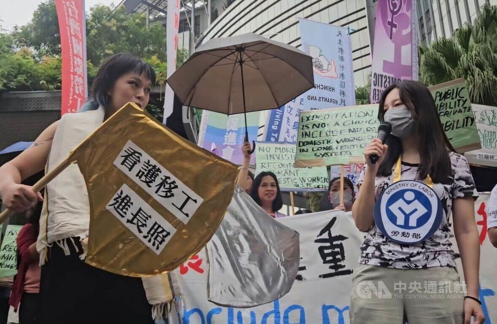 共同行動團體14日在衛福部前演出行動劇，指湖中女神「衛福部」（左）藏起象徵「機構聘僱家事移工」的金斧頭，任由公共長照議題淪為雇主與移工的勞資糾紛與弱弱相殘。 圖：中央社提供