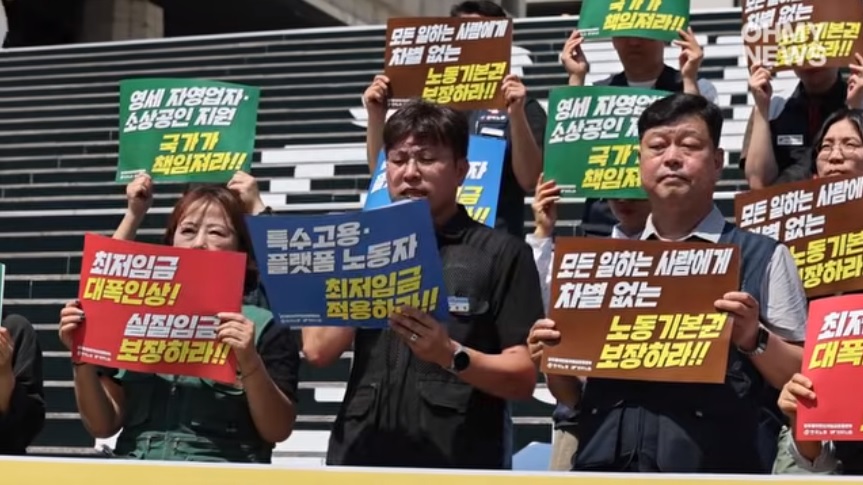 韓國兩大勞工團體 15 日聚集在首爾世宗文化會館前舉行記者會，要求政府 2027 年將最低薪資上調至 1.2 萬韓元，漲幅高達 16.3% 。 圖：截取自「YouTube」오마이TV頻道