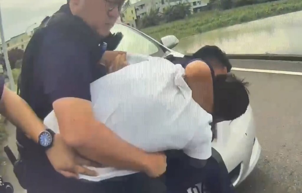 因多起案件遭通緝逃亡1年多的朱姓男子（白衣）17日開車途經台南市七股區時被警方攔查，朱男奮力抗拒，遭4名警員當場壓制、解送歸案。（台南市警察局提供）中央社記者張榮祥台南傳真　115年6月18日