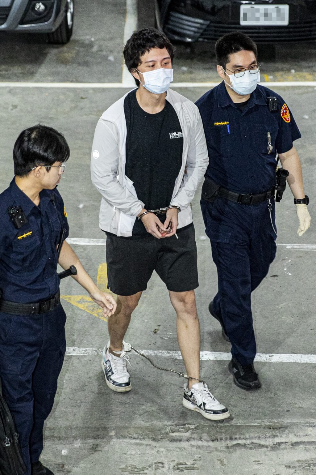 演員孫鵬兒子孫安佐（已改名孫健豪）（中）涉與陳姓男子在河堤旁測試自製噴火槍並張貼影片，遭士林地檢署搜索拘提。士林地方法院17日下午裁定羈押禁見。孫安佐在法警戒護下搭乘警備車。中央社記者鄭清元攝　115年5月17日