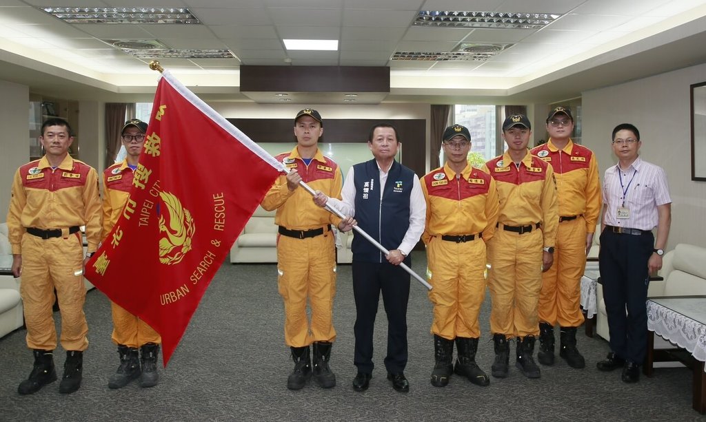台北市消防局表示，搜救隊股長徐孝允（中左）7月將率4名成員赴日參加綜合防災訓練暨技術交流，消防局長莫懷祖（中右）29日授旗。（台北市消防局提供）中央社記者黃麗芸傳真　115年6月29日
