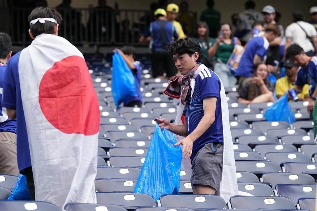 日本隊在世界盃足球賽32強以1比2遭巴西隊淘汰，日本球迷失落之餘仍依慣例在賽後自發性地收拾垃圾。（美聯社）