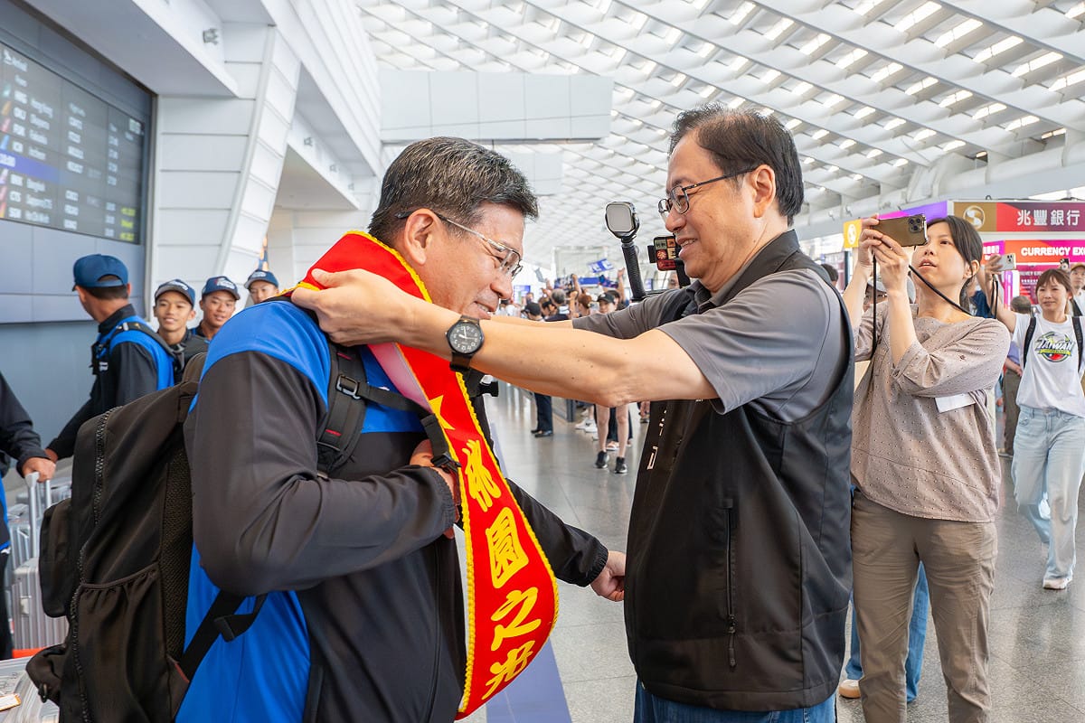 桃園市長張善政前往桃園國際機場，迎接新明國中棒球隊凱旋返台，並為隊職員披上歡迎彩帶。 圖：桃園市政府提供