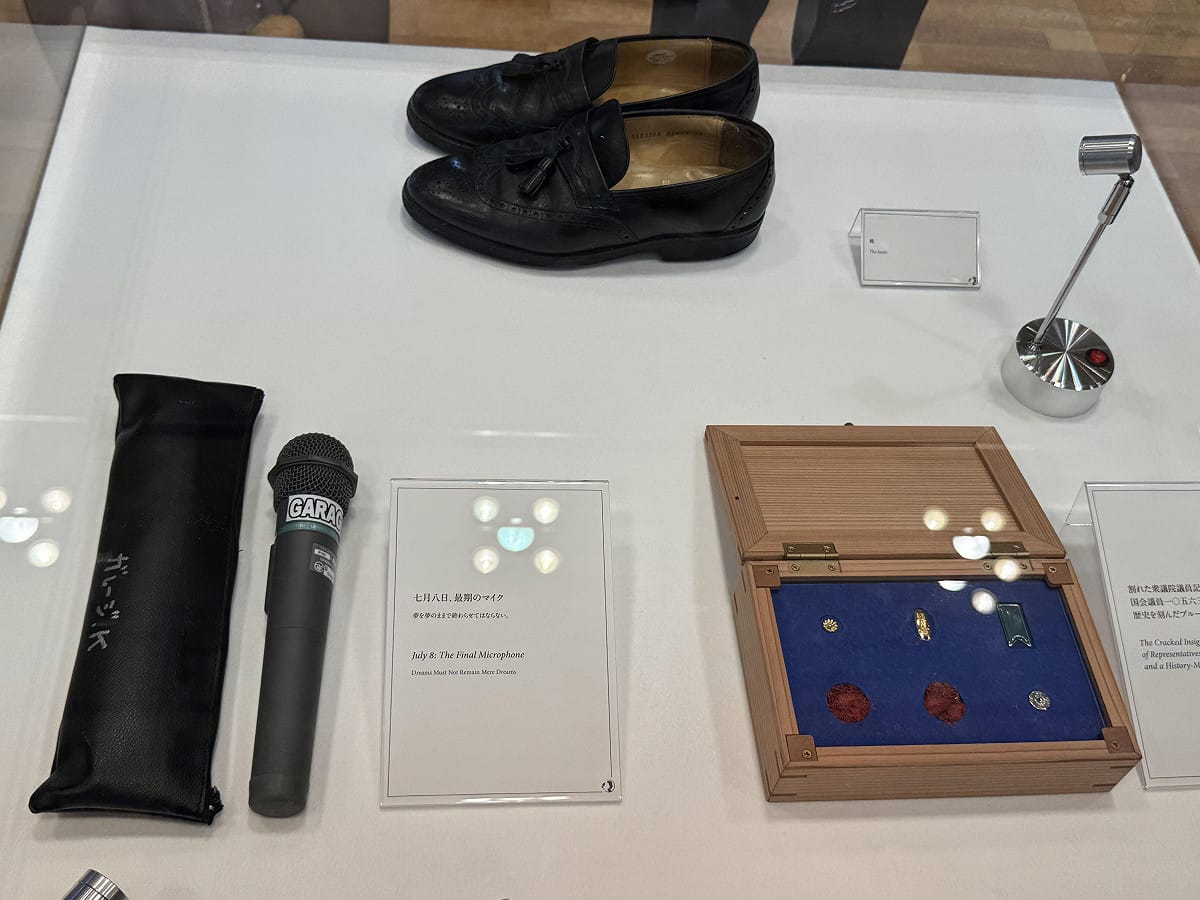 此次展覽共展出約100件珍貴遺物，其中最受矚目的，是安倍於2022年7月8日在奈良街頭演說遇襲時所使用的麥克風、當時穿著的皮鞋，以及因槍擊而碎裂的眾議員徽章。 圖：駐日代表處/提供
