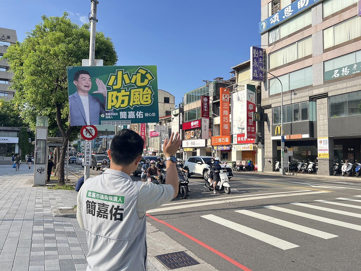 台中市北區市議員候選人簡嘉佑今（9）日站路口時舉起「小心防颱」的手舉牌，呼籲民眾密切關注氣象署所發布的最新颱風動態。 圖：簡嘉佑/提供
