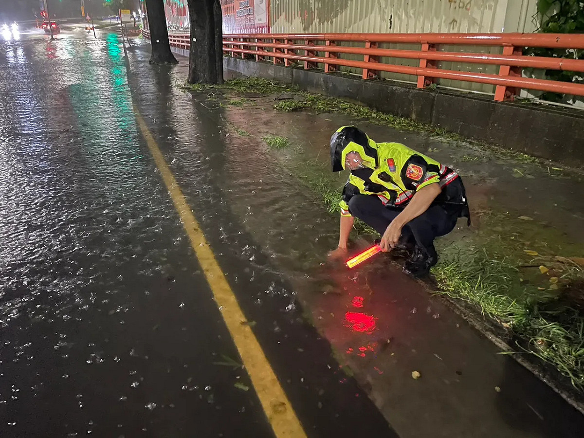 員警冒著颱風的風雨徒手清水溝。 圖：翻攝畫面