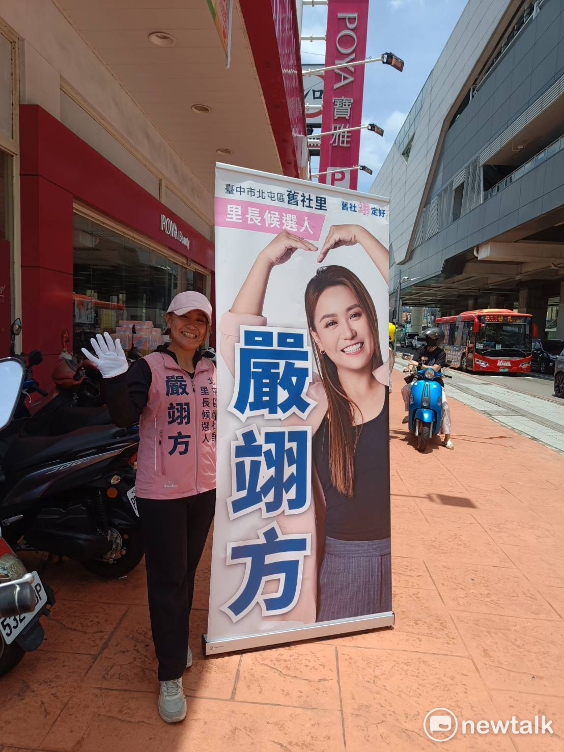 縱使烈日當頭、氣溫持續飆高，嚴翊方依然選擇在路口，獨自一人頂著高溫高舉大型宣傳看板，面帶微笑向路過的市民揮手問候。 圖：唐復年/攝