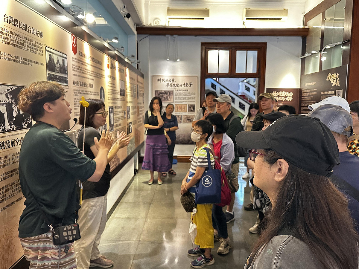 「台灣農民組合運動百年特展」策展團隊賴弘晉（左）導覧牛背上的鬥士簡吉生平。 圖：國家人權博物館提供