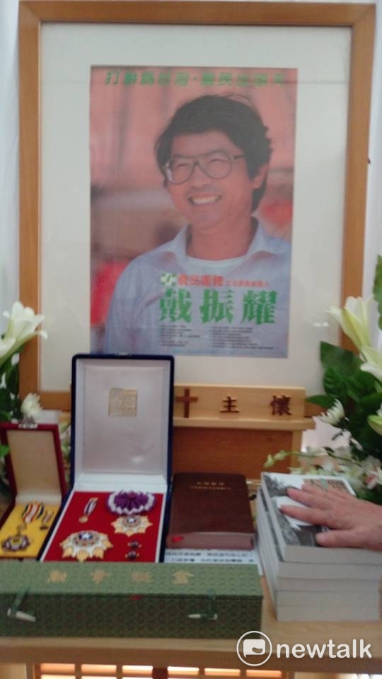 戴振耀靈堂的遺照，選用他最愛的1989競選農民團體立委時的照片，案前擺置蔡英文總統頒授的勳章及《鹽水大飯店—戴振耀的革命青春》新書的樣書。 圖：翻攝自邱萬興臉書