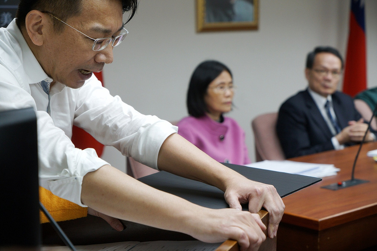 時代力量立委徐永明緊抓著發言台，深怕被民進黨立委架離發言台。 圖：張良一／攝