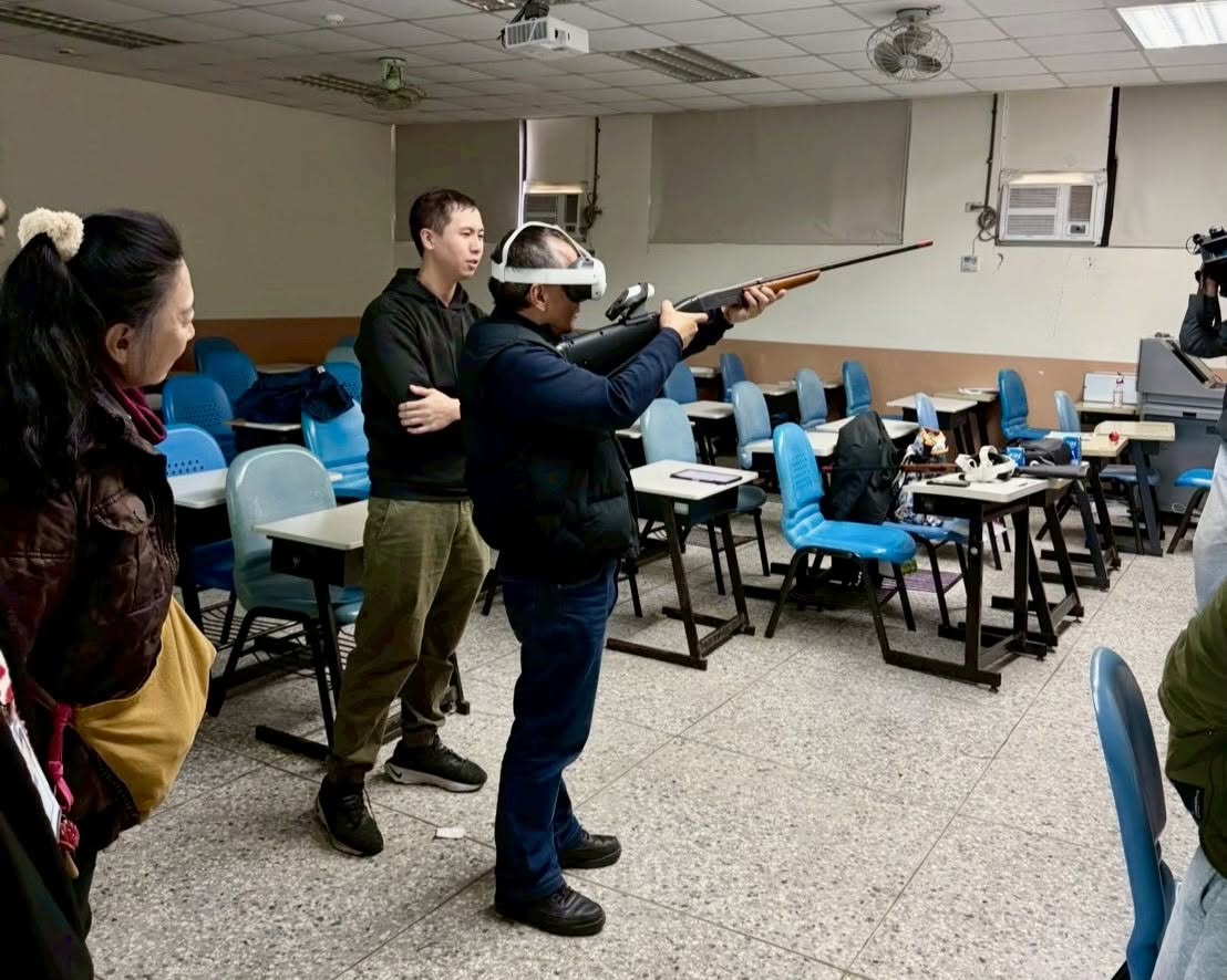 受訓學員配戴VR裝置，手中握著模擬真實槍枝重量與構造的獵槍操作器，在免除實彈危險的教室環境中進行「飛靶訓練」與「獵場環境模擬用槍訓練」。 圖：翻攝自原住民族委員會臉書