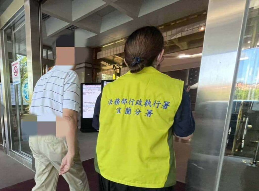 71歲營造公司負責人羅姓男子（左），得知欠繳勞保費新台幣518萬餘元後，涉嫌處分公司逾4000萬元資金卻不繳欠費，17日經執行官訊問後依法留置，並向宜蘭地方法院聲請管收獲准。（法務部行政執行署宜蘭分署提供）中央社記者王朝鈺傳真 115年8月18日