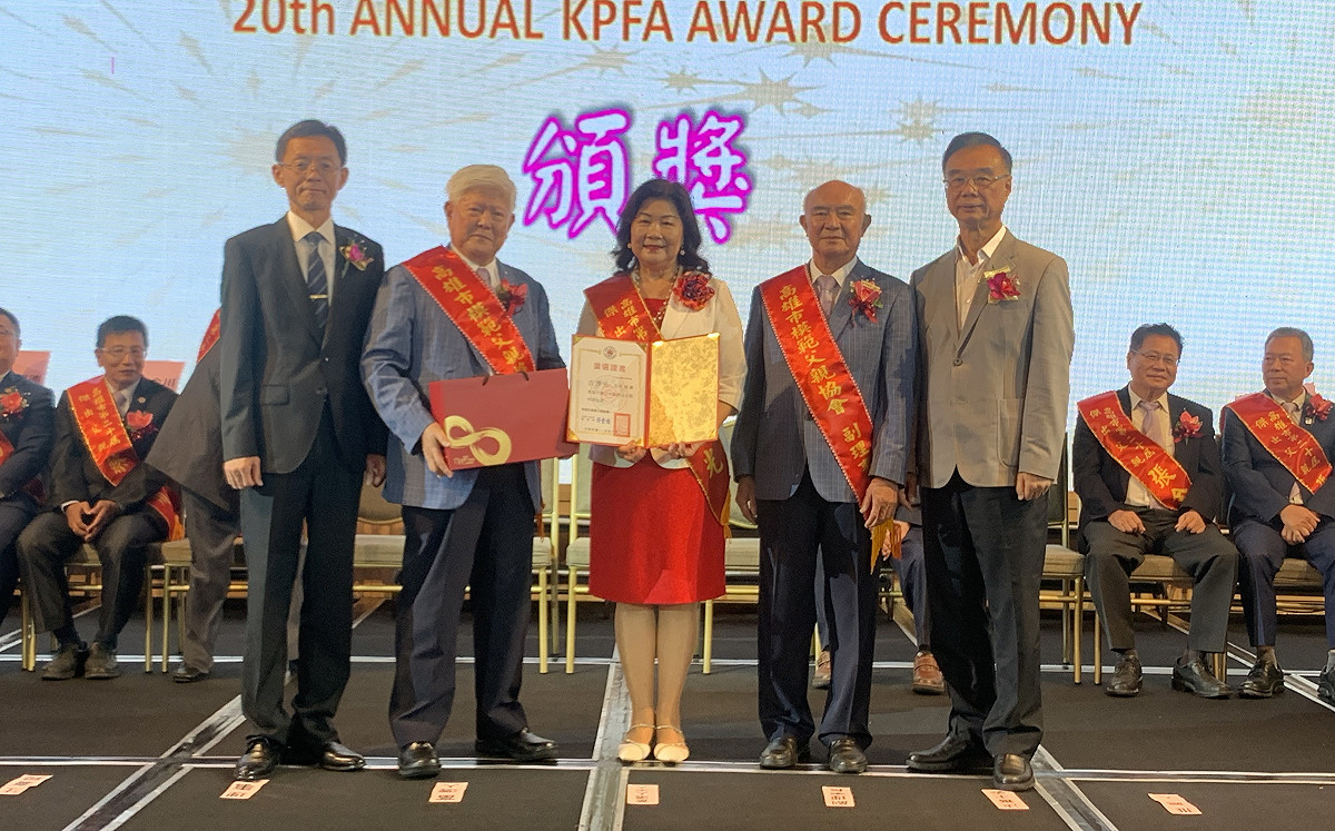 邱綉惠(中)代表公差不克出席的先生古源光上台領取當選證書與禮品。 圖：孫家銘攝