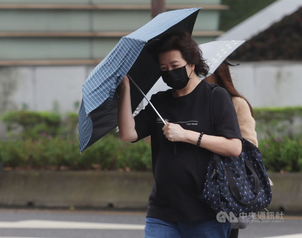圖為台北市信義區街頭民眾撐傘遮擋雨勢。（中央社檔案照片）