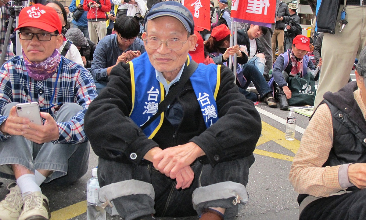 老政戰犯白雅燦4日靜靜坐在人群支持工會團體。 圖：林朝億/攝
