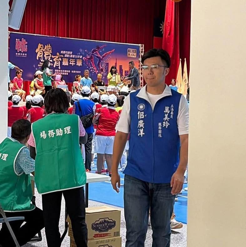 桃園市政府指導的「桃園體育嘉年華」，議員都不能進去的場，但佀廣洋換上「萬美玲服務團隊」背心就成功闖進，還被主持人介紹。 圖：取自沈佩玲臉書