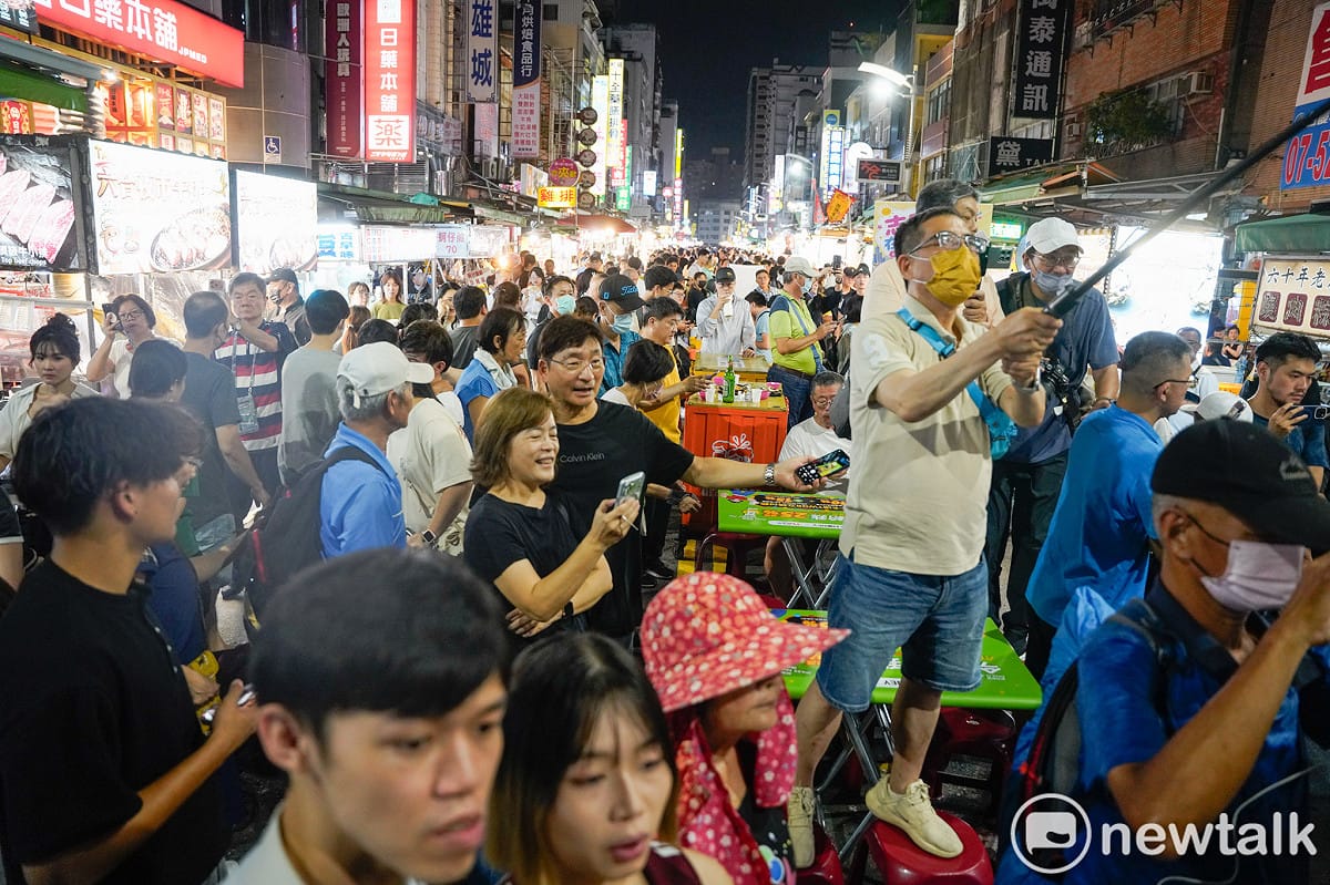 週末晚上的六合夜市人潮擁擠，一位支持者站在椅子上用影像紀錄蔣、柯兩人在夜市掃街情況。 圖：張良一/攝
