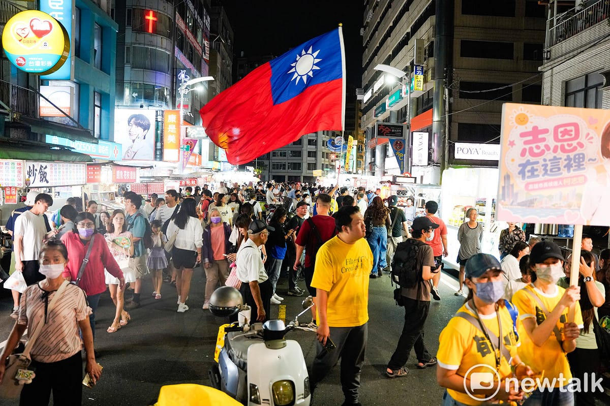 柯志恩支持者高舉巨幅國旗擔任蔣萬安與柯志恩掃街拜票的前導，並用力揮舞國旗以吸引民眾的目光。 圖：張良一/攝