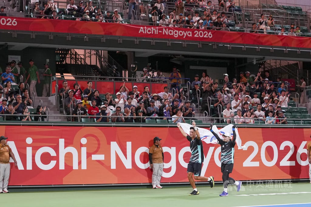 名古屋亞運軟式網球混雙項目21日登場，台灣組合余凱文（前左）、黃詩媛（前右）成功摘下金牌，賽後共同舉起中華奧會會旗繞場，觀眾在看台上熱烈鼓掌。中央社　115年9月21日