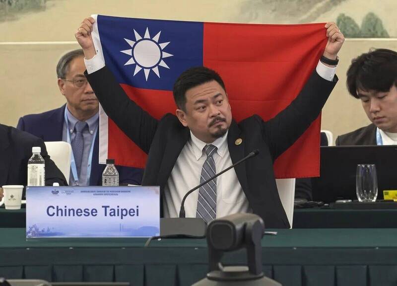 勞動部長洪申翰日前前往赴中國參加APEC人力資源發展部長會議，網路上卻流傳他在會場高舉中華民國國旗的照片，但有網友發現該張照片是AI合成的假照片，且發文帳號疑似來自中國。 圖：翻攝threads