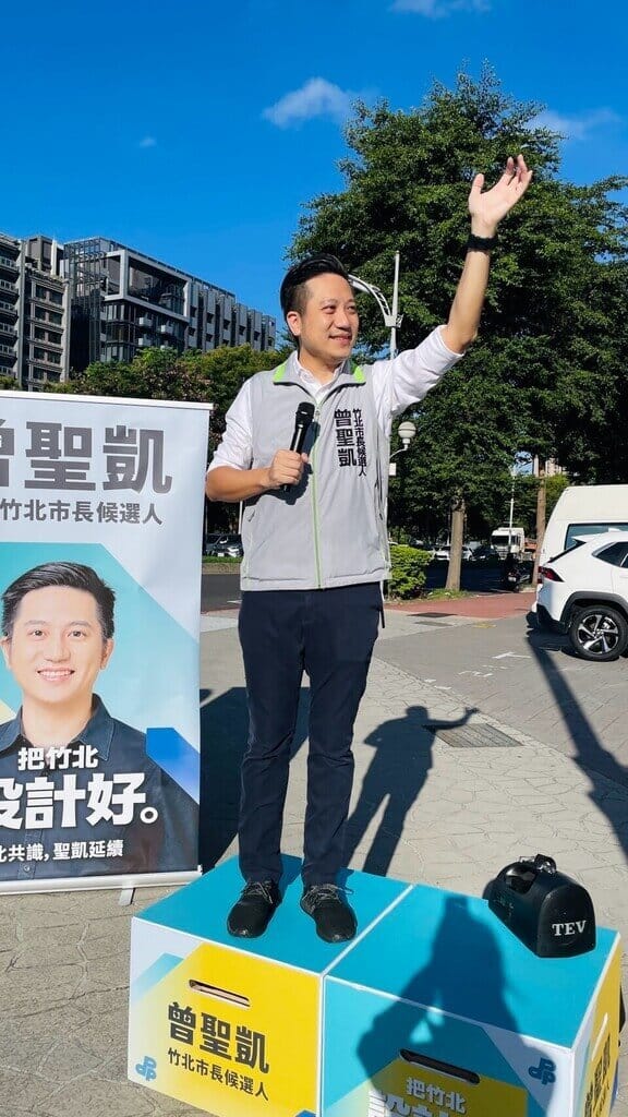 竹北市長選戰升溫，民進黨竹北市長參選人曾聖凱29日提出「停車e化2.0」，將整合竹北公有停車場位置、剩餘車位及電動車充電設施等資訊，並持續提升快、慢充設備便利性，減少市民尋找車位及充電設施時間。圖為曾聖凱站路口拜票。（曾聖凱提供）中央社記者郭宣彣傳真　115年9月29日