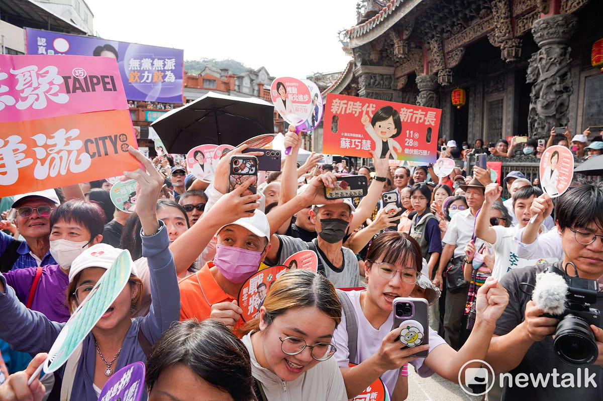 蘇巧慧和沈伯洋抵達三峽祖師廟時，民眾高舉手機拍攝或向兩人揮手加油打氣。 圖：張良一/攝