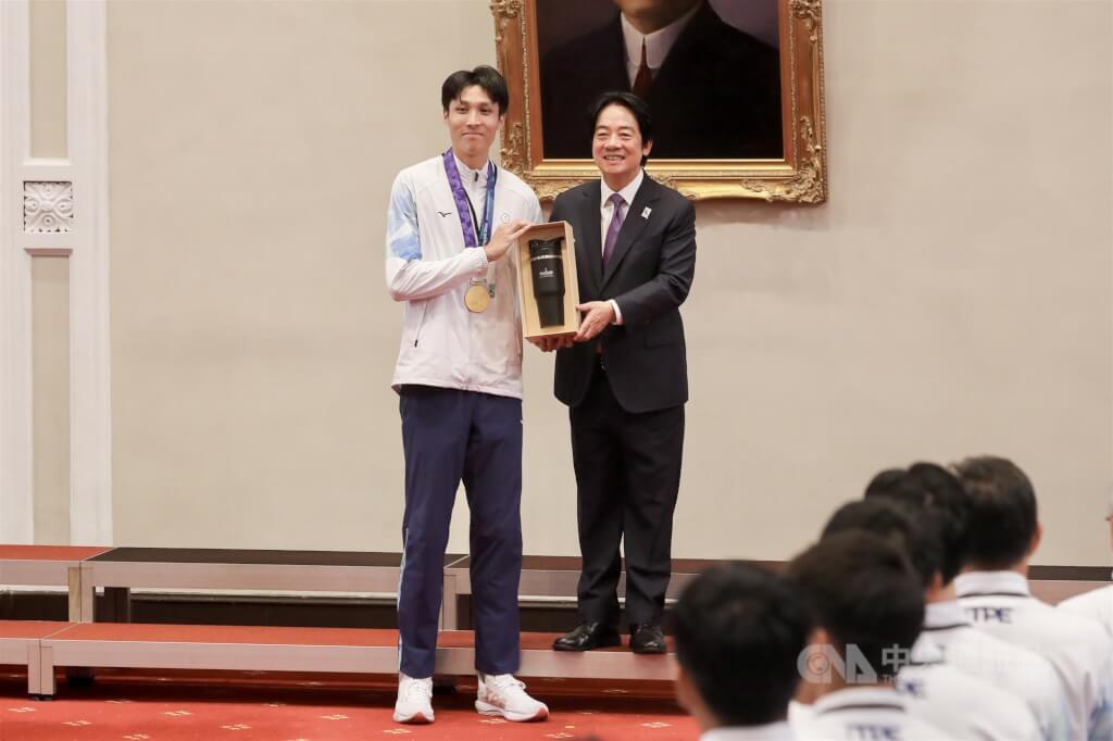 總統賴清德（右）6日在總統府接見我國參加「2026年第20屆愛知名古屋亞洲運動會」代表團，亞運金牌跳高選手傅兆玄（左）代表接受總統府致贈禮品。中央社記者裴禛攝 115年10月6日