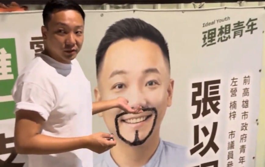 張以理競選看板被人劃了單邊鬍子，不僅沒有氣憤提告，反而親自帶畫筆將另一邊的鬍子「補齊」成為山羊鬍。 圖：張以理競辦／ 提供