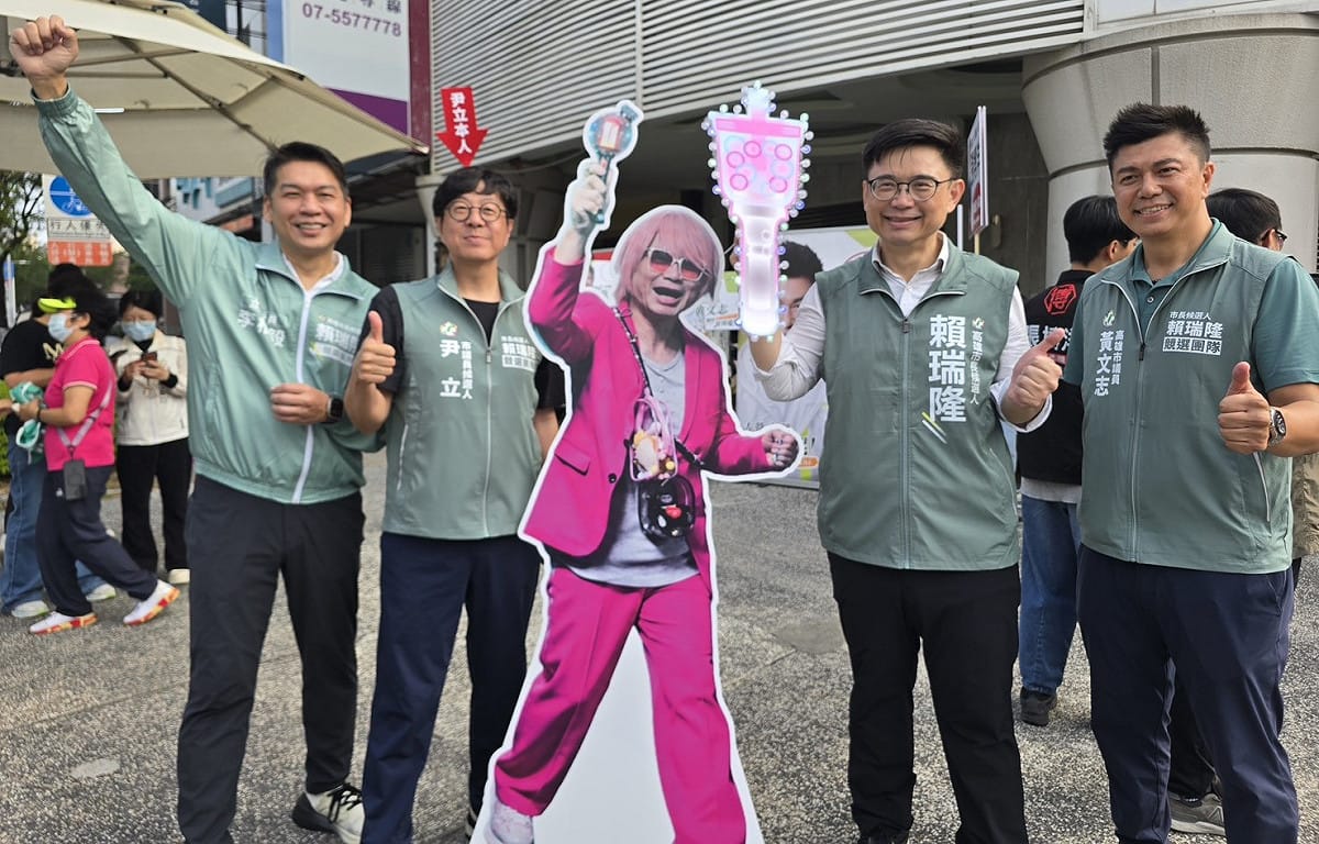 賴瑞隆(右二)競選廣告「百變隆隆」中的「權志隆」人形立牌，與本尊一同站路口， 圖：尹立競辦／提供