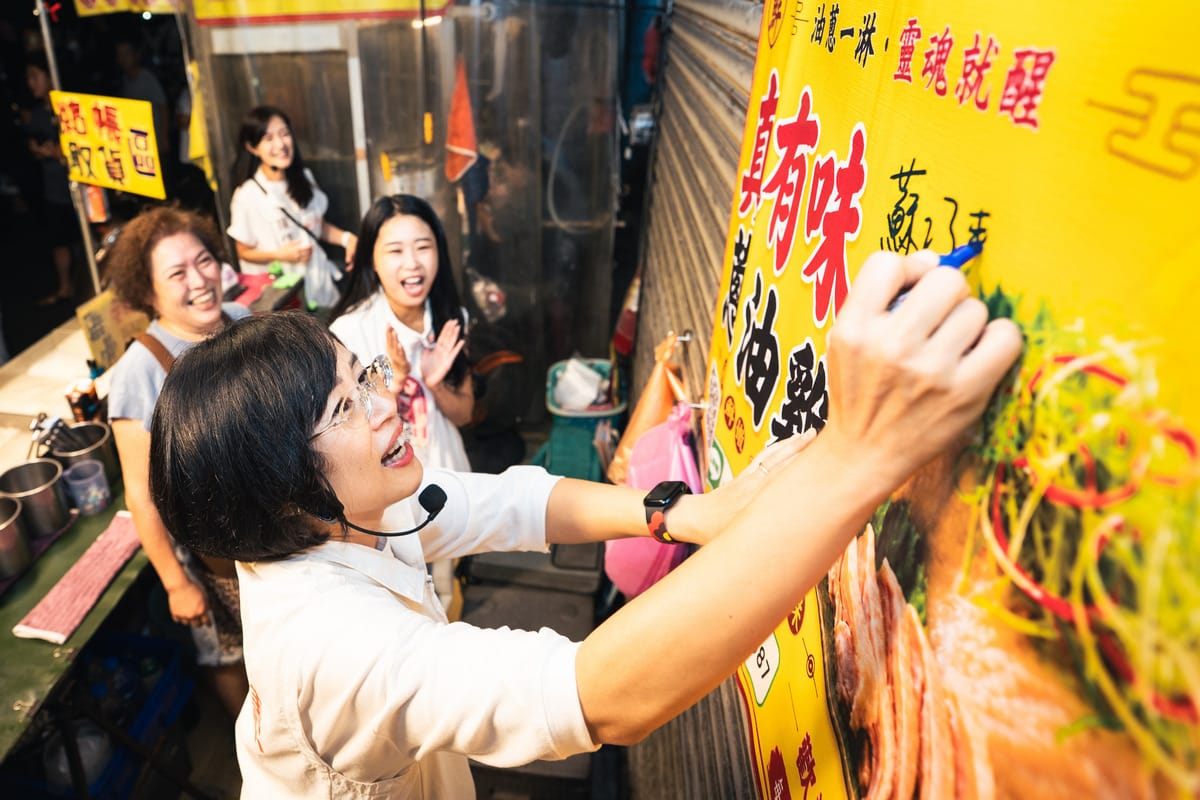 夜市攤商請蘇巧慧在店名海報上簽名。 圖：蘇巧慧競總提供