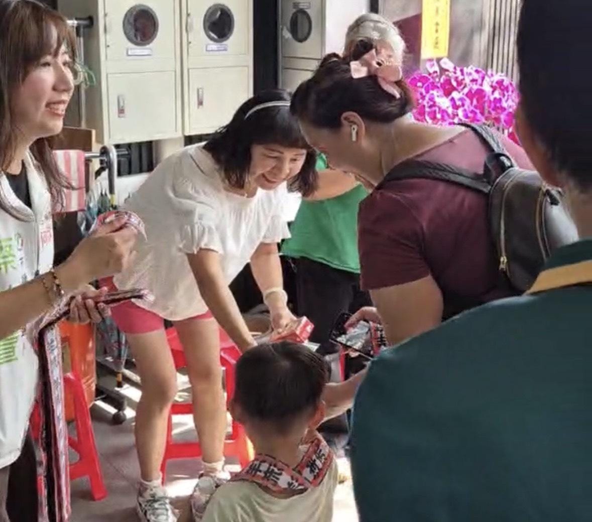 許多爸爸媽媽帶著孩子專程來拍照互動，其中一位小朋友在媽媽懷裡高舉小手、戴著亮眼飄帶為蔡怡萱打氣的童趣模樣，瞬間融化全場。 圖：蔡怡萱競總/提供