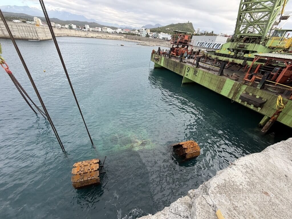 停放在台東富岡港堤防的大型吊車，日前遭颱風薔琵掀起的滔天巨浪打落港嘴，業者委請高雄大型拖吊平台船到富岡港實施拖吊作業，力拚28日完成拖吊上岸。中央社記者盧太城台東攝　115年10月28日