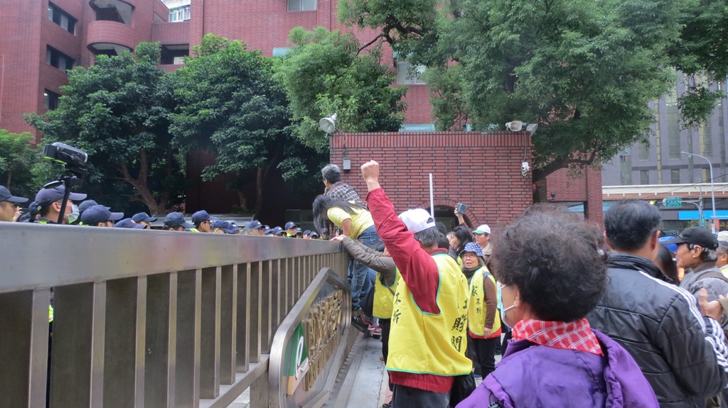 民眾強烈反彈航空城都委會欲再次舉行聽證會，有民眾爬上牆表示憤怒。 圖：環境法律人協會/提供