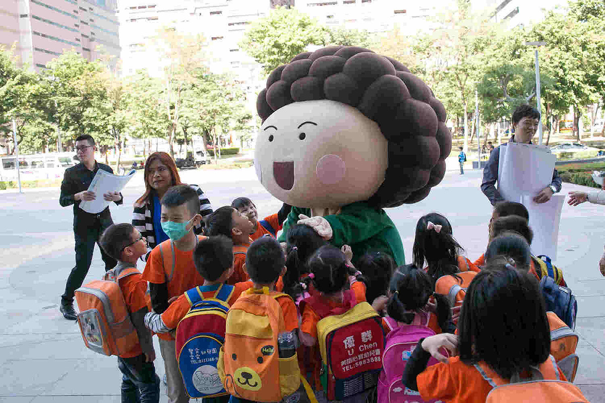 花媽人偶帶著高雄市2018特色年曆，在總圖前快閃發放。 圖：高雄市政府/提供